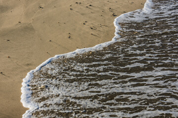 white foam in the water from the sea with a sandy beach