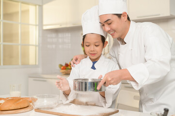 Young Asian father and his son wearing chef uniform baking together in kitchen at home