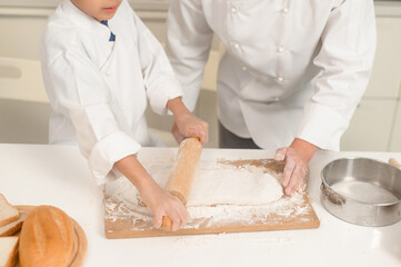 Young Asian father and his son wearing chef uniform baking together in kitchen at home
