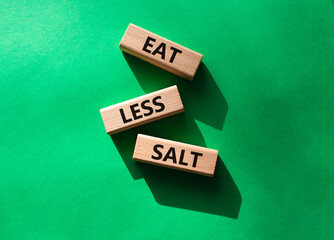 Eat less salt symbol. Concept word Eat less salt on wooden blocks. Beautiful green background. Business and Eat less salt concept. Copy space