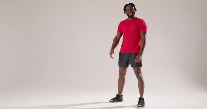 sporty fit cheerful bearded African man wears red t-shirt blue shorts l waving hand, asking to visit sport center or fitness club meet greet as notices someone isolated on white background studio