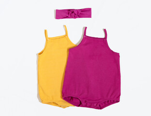 Summer outfit. Baby vest bodysuit yellow and pink color with head accessories. Top view, flat lay on white.