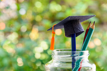 Back to school or graduate certificate program concept : Black graduation cap and a pencil in a...
