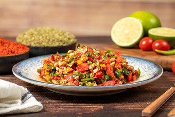 Gavurdagi salad. Walnut salad on wood background. Healthy salad prepared with tomatoes, peppers, cucumbers, onions, pomegranate syrup, olive oil and walnuts