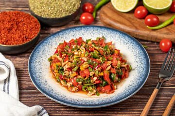 Gavurdagi salad. Walnut salad on wood background. Healthy salad prepared with tomatoes, peppers, cucumbers, onions, pomegranate syrup, olive oil and walnuts
