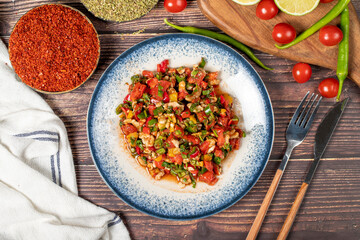 Gavurdagi salad. Walnut salad on wood background. Healthy salad prepared with tomatoes, peppers, cucumbers, onions, pomegranate syrup, olive oil and walnuts. Top view