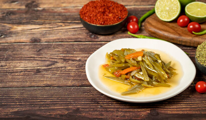 Green bean dish with olive oil on wood background. Empty space for text. Copy space