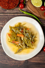 Green bean dish with olive oil on wood background. Top view