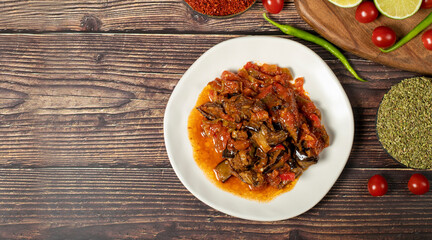 Eggplant dish with vegetables fried in olive oil on a wooden floor. Top view. Empty space for text. copy space