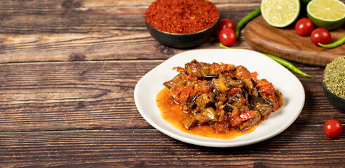 Eggplant dish with vegetables fried in olive oil on a wooden floor. Empty space for text. copy space
