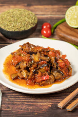Eggplant dish with vegetables fried in olive oil on a wooden floor. Close up