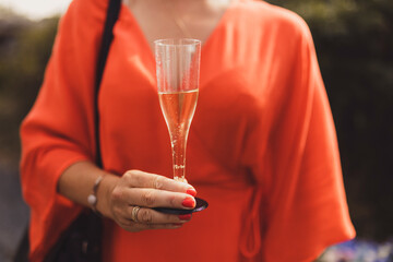 Woman in red dress holding a glass of champagne.