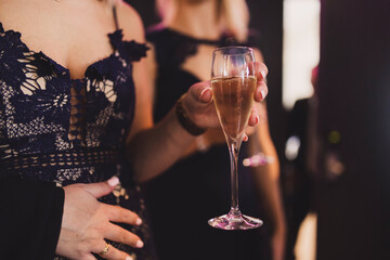 Woman in dark dress holding a glass of champagne at a party.