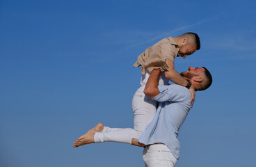 Man holding up his boyfriend while enjoying together outdoors.