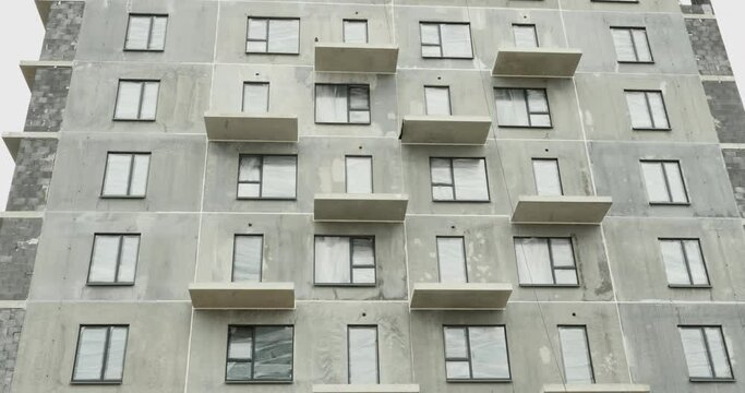 Stages of construction of an apartment building. A newly built apartment building with a large number of apartments. House made of concrete blocks with inserted windows. Concrete without finishing.