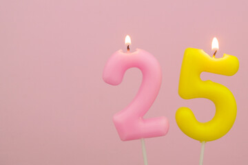 Birthday candles burning and melting on pink background. Number 25. Copy space for text.