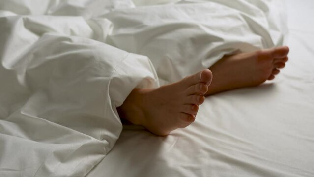 Close-up shot of feet of sleeping woman in bed