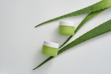 Aloe vera - (Aloe barbadensis) decorated on white background with two green cream jars unlabeled. Natural beauty blank label for branding mockup concept. Space for design