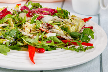 Fresh salad of cabbage, herbs, peppers, carrots and pomegranate seeds in a white plate.