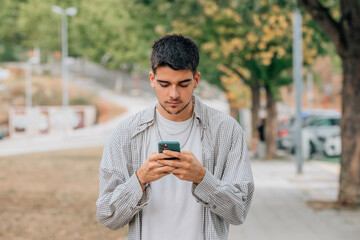 young male on the street walking looking at the mobile phone or smartphone