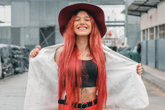 hipster girl with hat and red hair smiling on the street