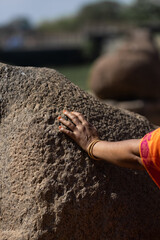 The woman touches a stone with her hand on a sunny day. Close-up of the hand. The concept of human and nature.