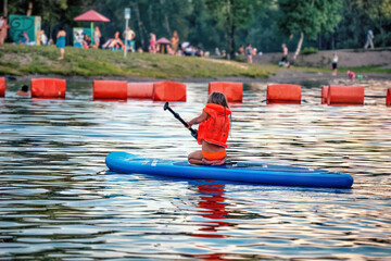 A girl sup surfing paddling on a boat on a river on sunny day. Motion blur. Soft focus.