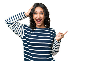 Young Argentinian woman over isolated background surprised and pointing finger to the side