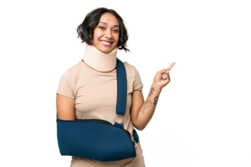 Young argentinian woman wearing neck brace and sling over isolated background pointing finger to the side
