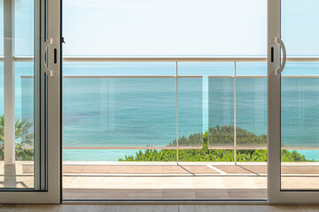 Breathtaking view from a hotel room through a panoramic window with a terrace to the sea on a sunny warm summer day with blue skies in a luxury resort. Concept of rest after a working year