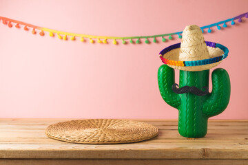 Empty wooden table with wicker place mat  and cactus decoration over pink wall  background. Mexican party mock up for design and product display