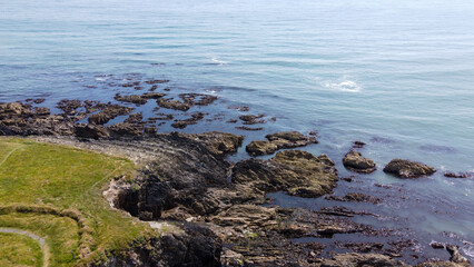 coast of the Atlantic Ocean in Ireland, top view. Rocky coast, seaside landscape. Irish nature. Green grass field on gray rocky mountain