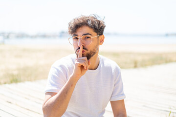 Handsome Arab man at outdoors With glasses and doing silence gesture