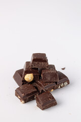 pieces of dark chocolate with hazelnuts on a white background, copy space
