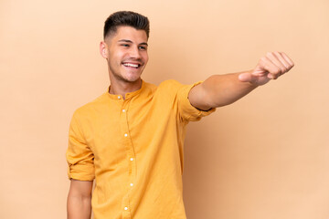 Young caucasian man isolated on beige background giving a thumbs up gesture