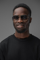 Fototapeta premium Studio shot of smiling guy of african ethnic dressed in trendy sunglasses and casual attire.