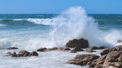 Powerful wave splashing against rocks on the Atlantic coast of Portugal in summer, sending spray  high into the air