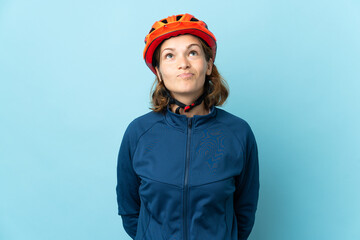 Young cyclist woman isolated on blue background and looking up
