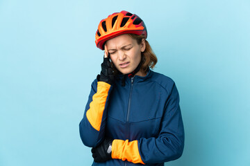 Young cyclist woman isolated on blue background with headache