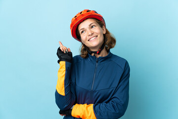 Young cyclist woman isolated on blue background pointing up a great idea