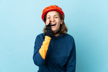 Young cyclist woman isolated on blue background shouting with mouth wide open
