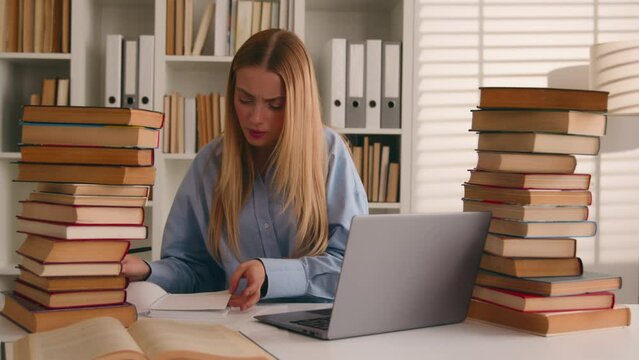 Busy Caucasian student girl stressed leaner pupil woman studying with laptop and books homework learning online search information knowledge problem prepare for test exam study at university library