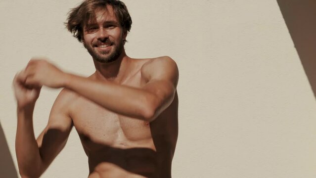 Handsome strong man. Healthy athletic fitness model posing near white wall in jeans. Sexy fashion male with naked nude torso. Lambersexual outdoors 