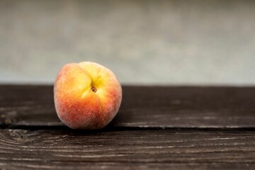 Closeup of a peach on the wooden table.