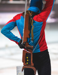 Biathlete with rifle on a shooting range during biathlon training, skiers on training ground in...