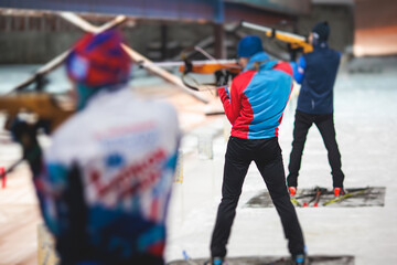 Biathlete with rifle on a shooting range during biathlon training, skiers on training ground in winter snow, athletes participate in biathlon competition on slope piste © tsuguliev