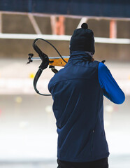 Biathlete with rifle on a shooting range during biathlon training, skiers on training ground in...