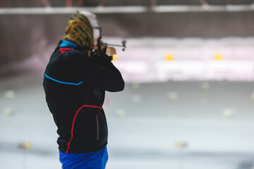 Biathlete with rifle on a shooting range during biathlon training, skiers on training ground in winter snow, athletes participate in biathlon competition on slope piste