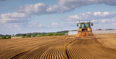 Agriculteur au volant de son tracteur labourant son champ de terre dans la campagne en France.