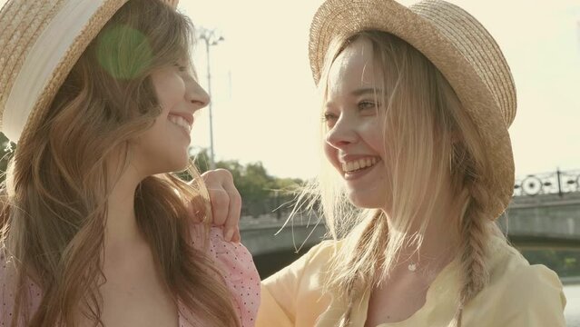 Two young beautiful smiling hipster woman in trendy summer sundress. Sexy carefree women posing in the street in hats